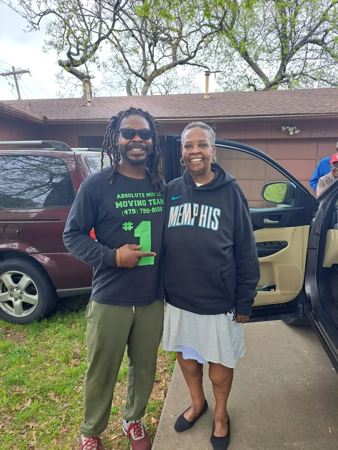 Moving team member and a woman smiling beside a parked vehicle