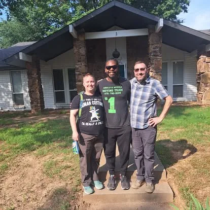 Moving team member with two people outside a house